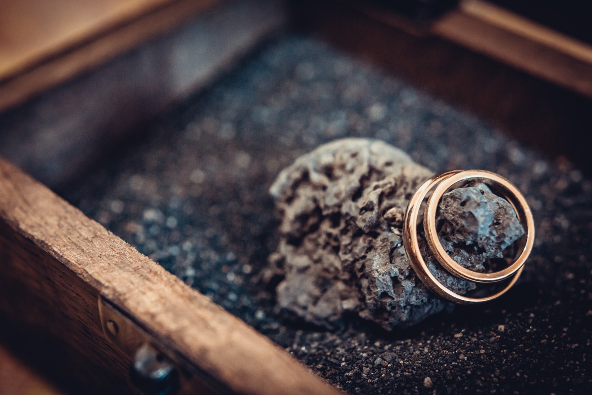 detalle de anillos de boda en su caja con arena negra