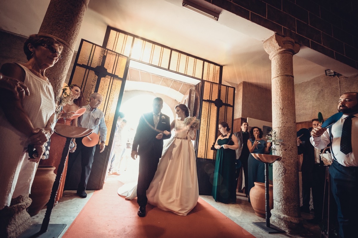 Entrada al interior de una iglesia de una novia con su padre mientras todos los invitados les miran