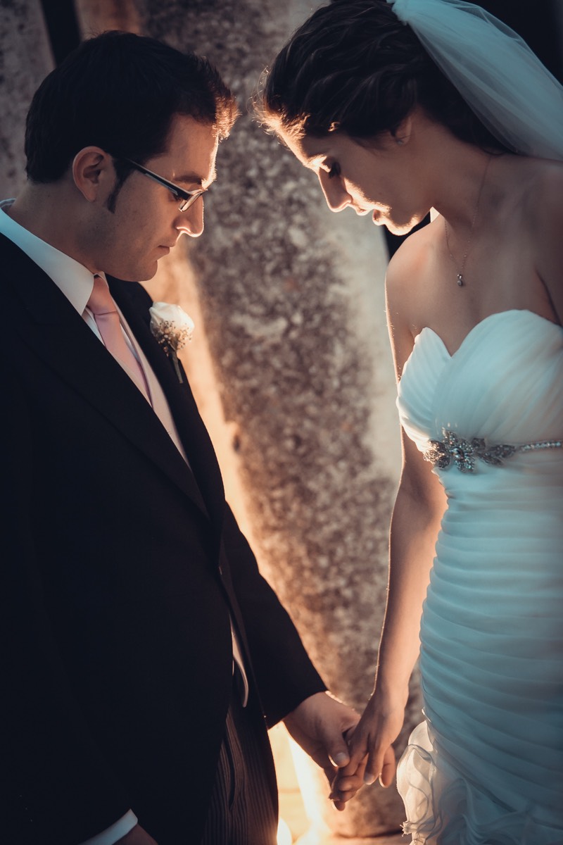 graciosa pose de una pareja de novios mientras se besan en un jardin durante su sesión de fotos de pareja en su boda