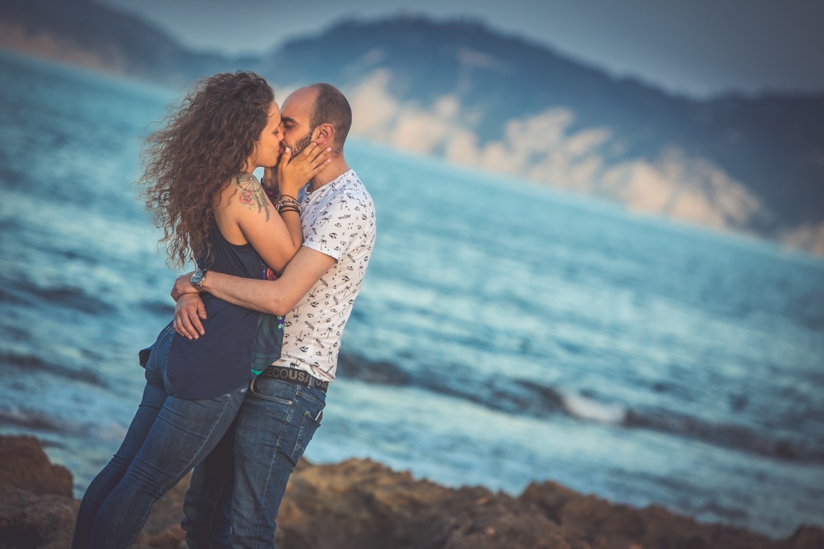 Divertido y bonito reportaje fotográfico de preboda realizado en Jávea, Alicante a orillas del mar. Novios besándose con el mar azul de fondo