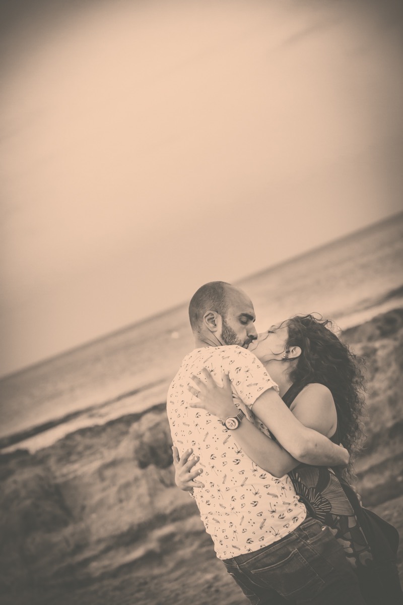 Divertido y bonito reportaje fotográfico de preboda realizado en Jávea, Alicante a orillas del mar. novios abrazados y besándose sobre las rocas y con el mar de fondo
